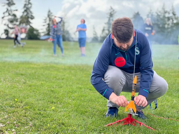 Andrew Samuelson a Strategic Weapons Facility-Pacific (SWFPAC) Science, Technology, Engineering, and Math (STEM) volunteer, prepares a test rocket for launch during an event with Ridgetop Middle School in early June. SWFPAC’s STEM program has supported four successful launches from 2023-2024, and volunteers ensure the safety of students during the rocket launches; assist with connecting launchers; fix faulty fuses; and answer questions about how rocket launches relate to SWFPAC’s real-world mission. SWPFAC is the command dedicated to assembling, maintaining, and storing TRIDENT II D5 Missiles and deploying them on fleet ballistic missile submarines (U.S. Navy Photo by Chani Wenning/Released)