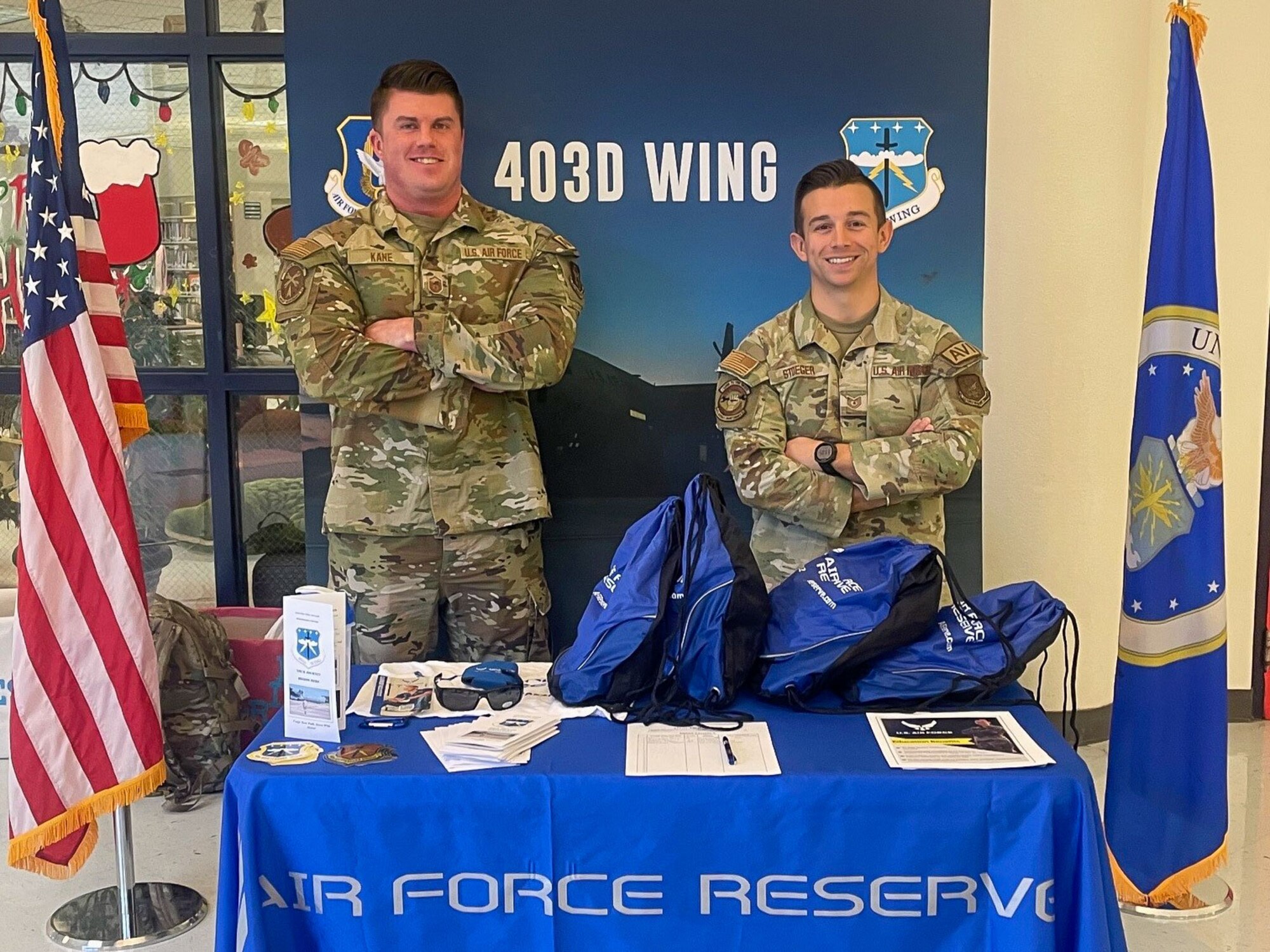 Two maintenance Airmen standing in front of recruiting table.