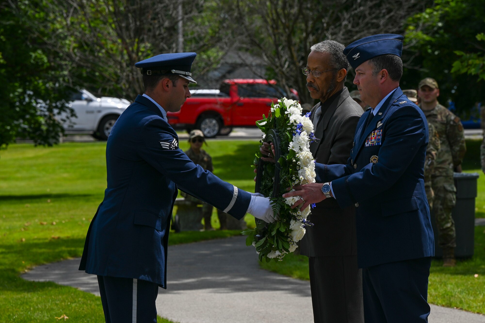 An Airman hands a wreath to two people.