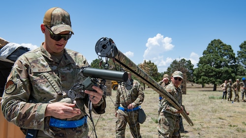 Two servicemembers manipulating a piece of equipment.
