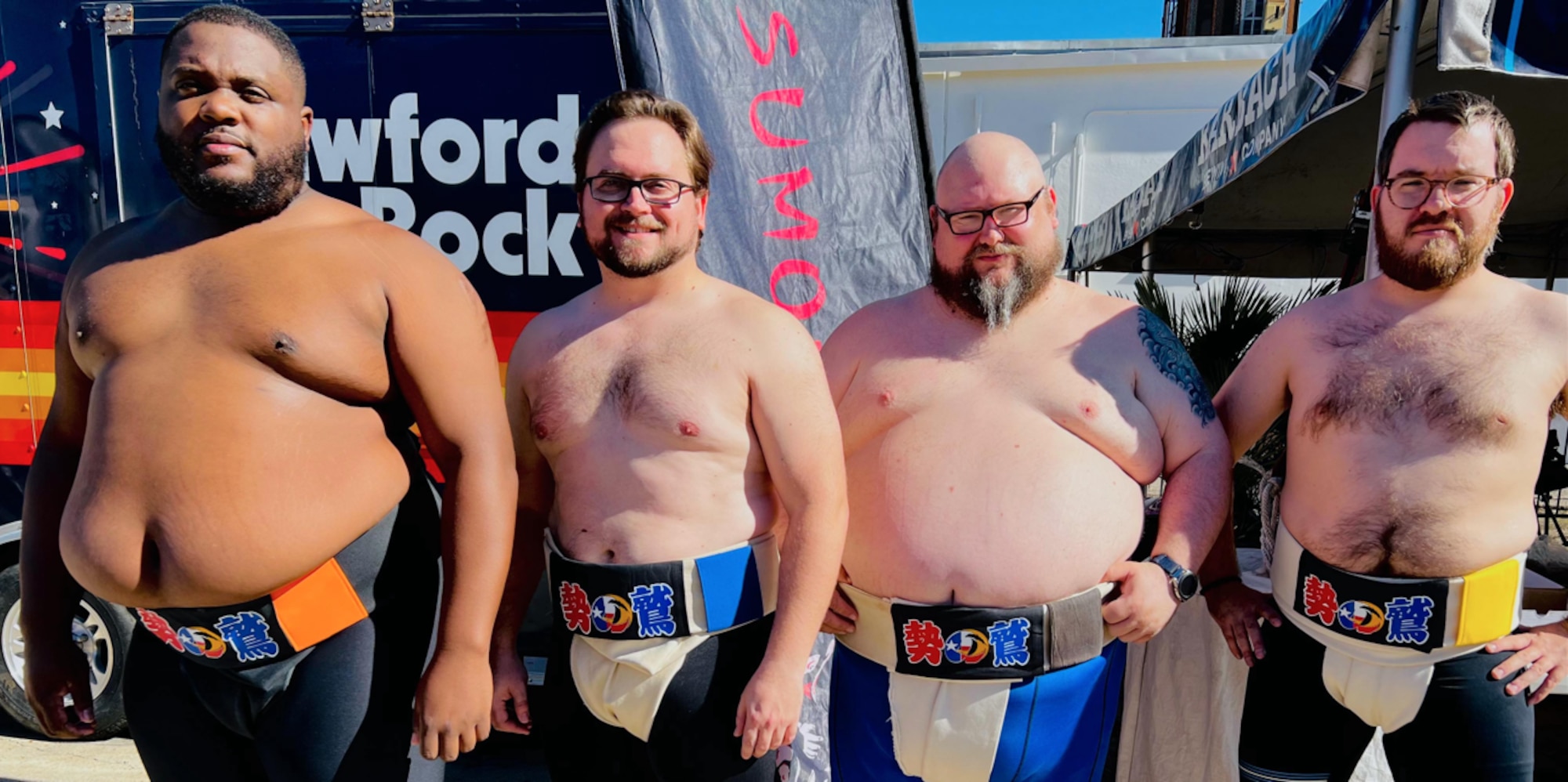 Photo of four wrestlers standing in sumo attire.