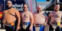 Photo of four wrestlers standing in sumo attire.