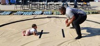 Scriven, at right, squats in the sumo position while his infant daughter crawls toward him in a sumo ring.