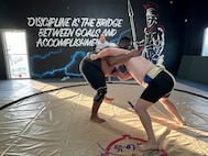 Scriven pictured at left grappling with his teammate while the stable's sensei looks on.