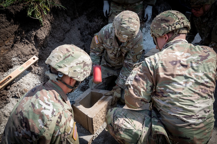 Engineers with the 130th Engineer support Company, 206th Engineer Battalion, Kentucky National Guard, set the foundation blocks for a retaining wall at Camp Dodge, Iowa on May 15, 2024. The 206th Engineer Battalion worked on various construction projects at Camp Dodge for their annual training.  (U.S. Army National Guard photo by Sgt. 1st Class Andrew Dickson)