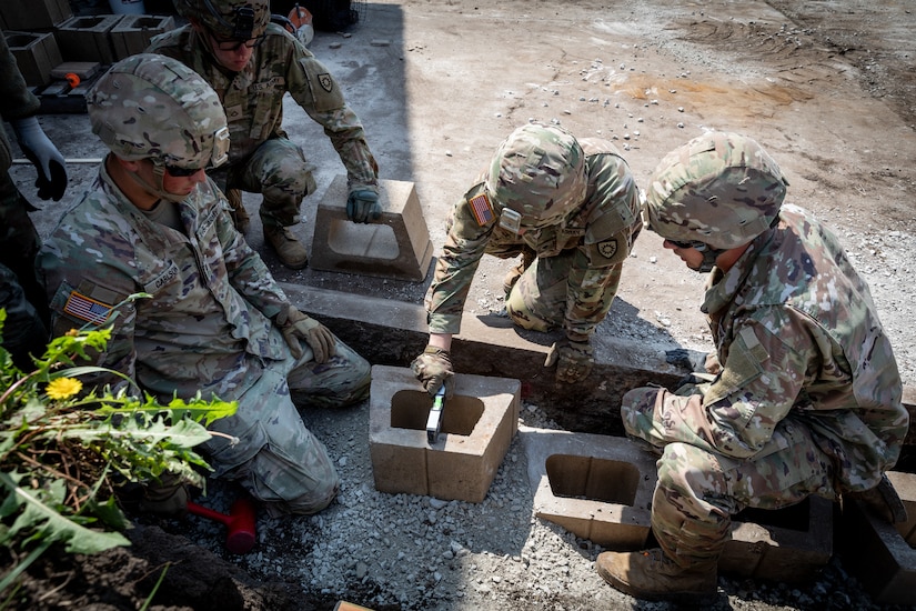 Engineers with the 130th Engineer support Company, 206th Engineer Battalion, Kentucky National Guard, set the foundation blocks for a retaining wall at Camp Dodge, Iowa on May 15, 2024. The 206th Engineer Battalion worked on various construction projects at Camp Dodge for their annual training.  (U.S. Army National Guard photo by Sgt. 1st Class Andrew Dickson)