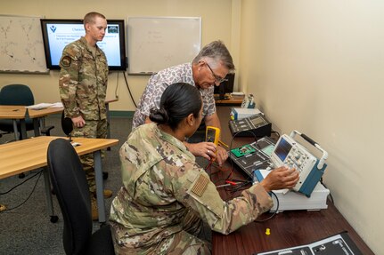 U.S. Air Force Ret. Senior Master Sgt. James Chapman, 334th Training Squadron Radar, Airfield & Weather Systems Specialist instructor, advises Airman 1st Class Rocio Trejo, 334th TRS RAWS student, during a practical application assignment on Keesler Air Force Base, Mississippi, June 20, 2024.