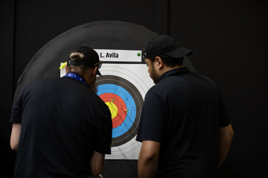 Miguel Avila watches as officials score his father, U.S. Army Cpt. Luis Avila's target during the archery event