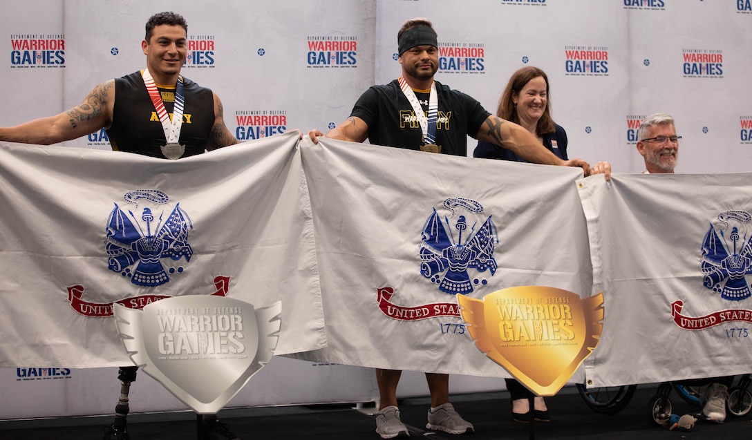 U.S. Army veterans Jason Smith, right, Shawn Lee, center, and Christopher Parks, far right pose for a photo after sweeping the medals for the 1 minute race at the indoor rowing event