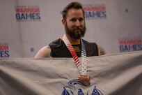 U.S. Army veteran Patrick Dayton poses for a photo with his bronze medal at the indoor rowing event