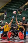 U.S. Army Staff Sgt. Abel Baez, right, reaches high for the ball during the tipoff to start a wheelchair rugby match