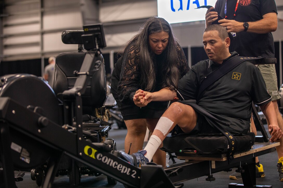 U.S. Army Cpt. Luis Avila receives assistance from his wife Claudia at indoor rowing practice