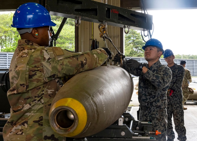 U.S. and foreign service members handle munitions.