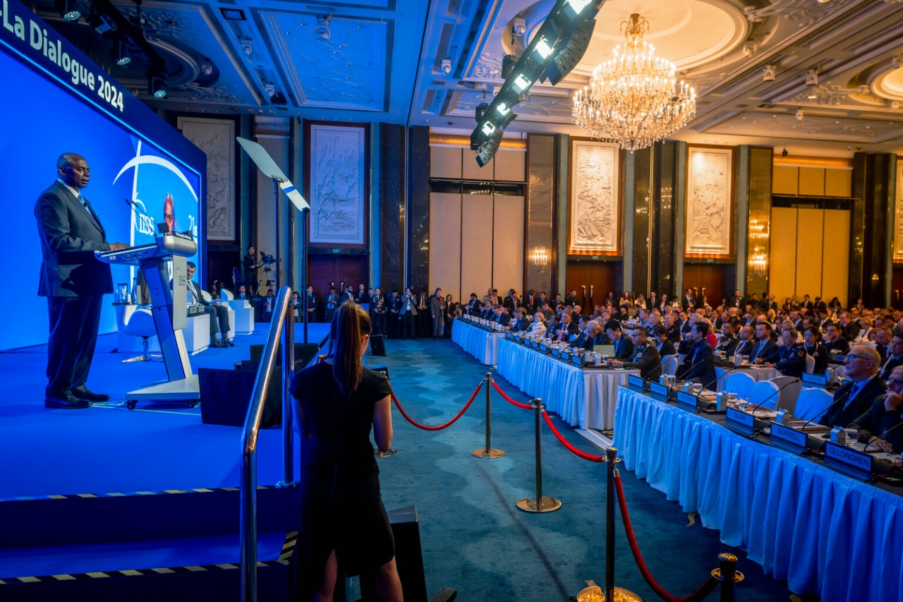 A man in a business suit stands at a lectern.