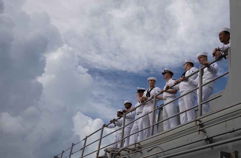 Sailors stand aboard a ship.