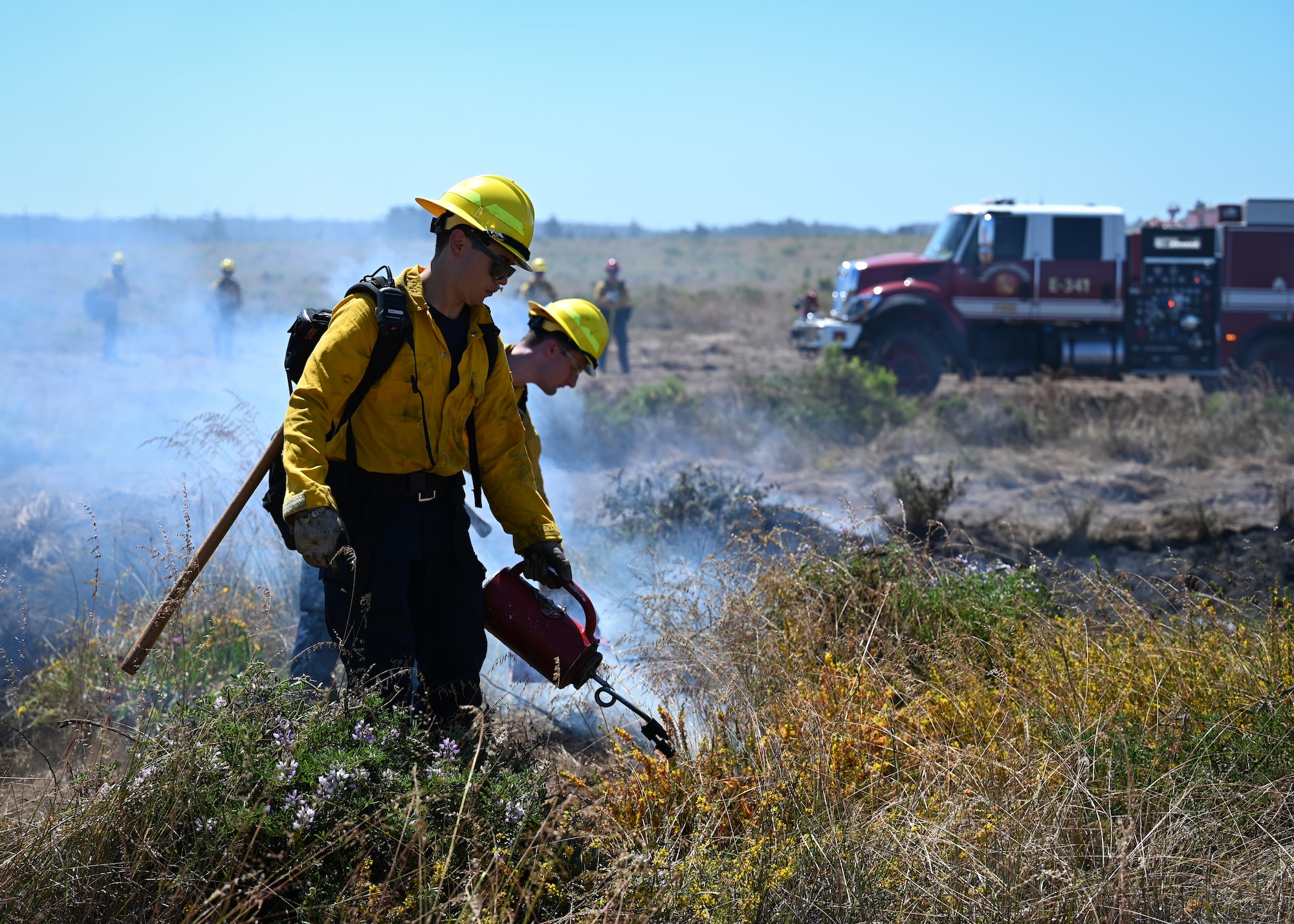 A man uses a fire drip torch to ignite a fire.