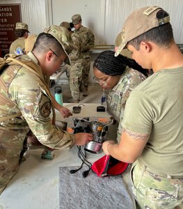 Four Airmen huddled around equipment on a work bench.