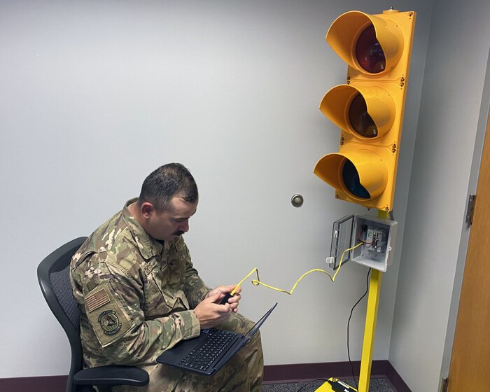 A man in a green service uniform operates a stoplight in the classroom.