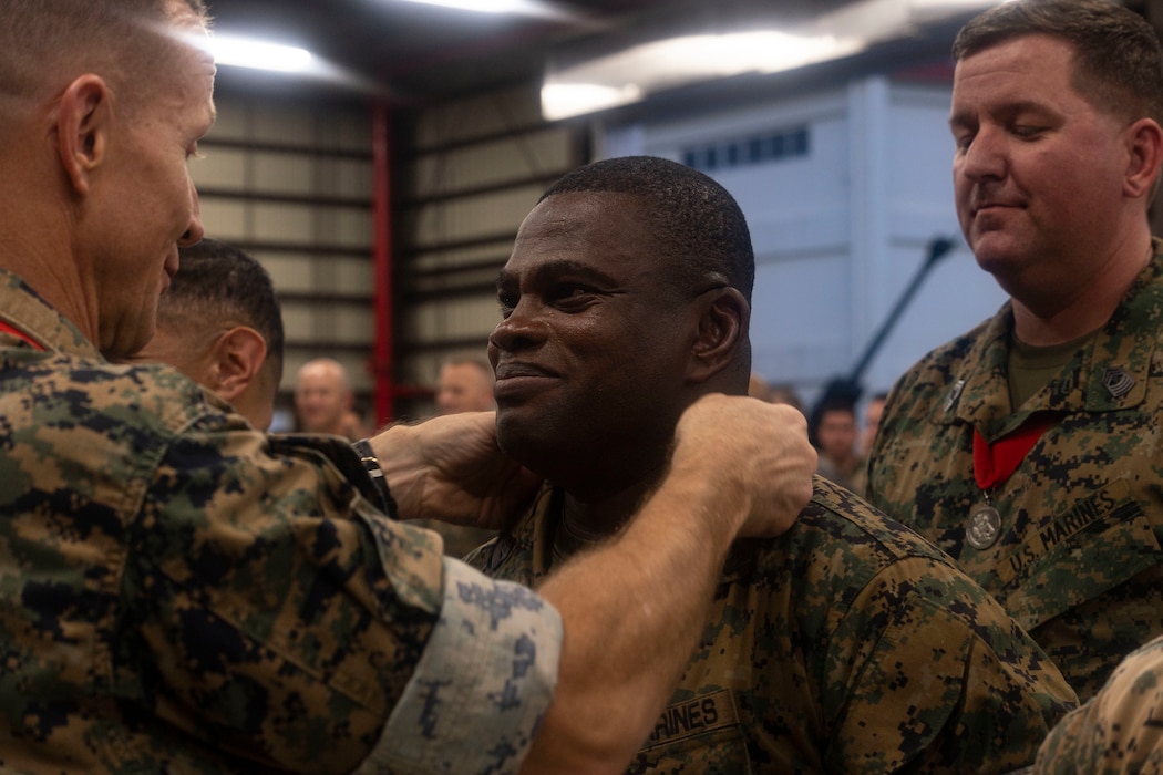 U.S. Marine Corps Maj. Gen. Stephen Liszewski, left, places the Honorable Order of St. Barbara around the neck of Sgt. Maj. Ismael Bamba, middle, during the St. Barbara’s Day ceremony on Camp Hansen, Okinawa, Japan, April 11, 2024. The St. Barbara’s day celebration is commemorated across artillery regiments in the armed forces to honor St. Barbara, the patron saint of artillerymen. The Honorable Order of Saint Barbara is awarded to individuals who have demonstrated the highest standards of integrity and moral character, displayed an outstanding degree of professional competence and served the Artillery with selflessness. Liszewski, a native of Maryland, is the commanding general of Marine Corps Installation Pacific. Bamba, a native of Ivory Coast, West Africa, is the sergeant major of the 12th Marine Littoral Regiment, 3d Marine Division. (U.S. Marine Corps photo by Cpl. Davin Tenbusch)