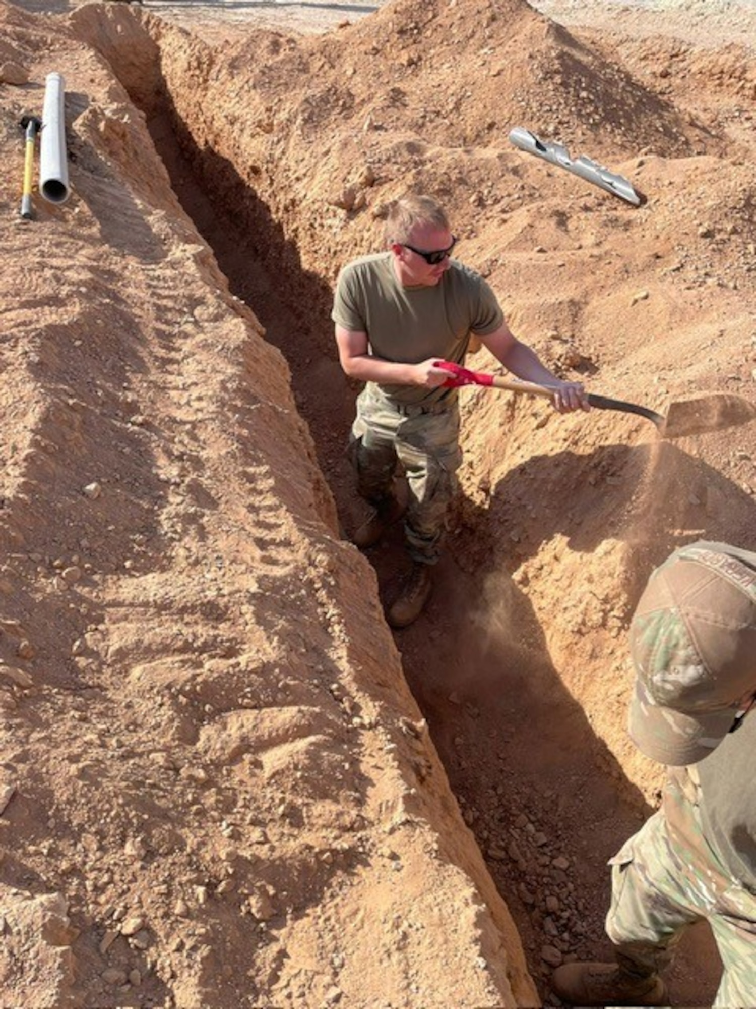 Airmen assigned to the 1st Expeditionary Theater Support Group dig a ditch for a conduit install at an undisclosed location within the U.S. Central Command area of responsibility, June 3, 2024. One of the ETSG’s main objectives is campaigning and setting the theater for Agile Combat Employment through prepositioning vital equipment, creating detailed bed down plans, contracting local support services, establishing communications nodes, and executing ground preparation engineering projects. (U.S. Air Force Courtesy photo)