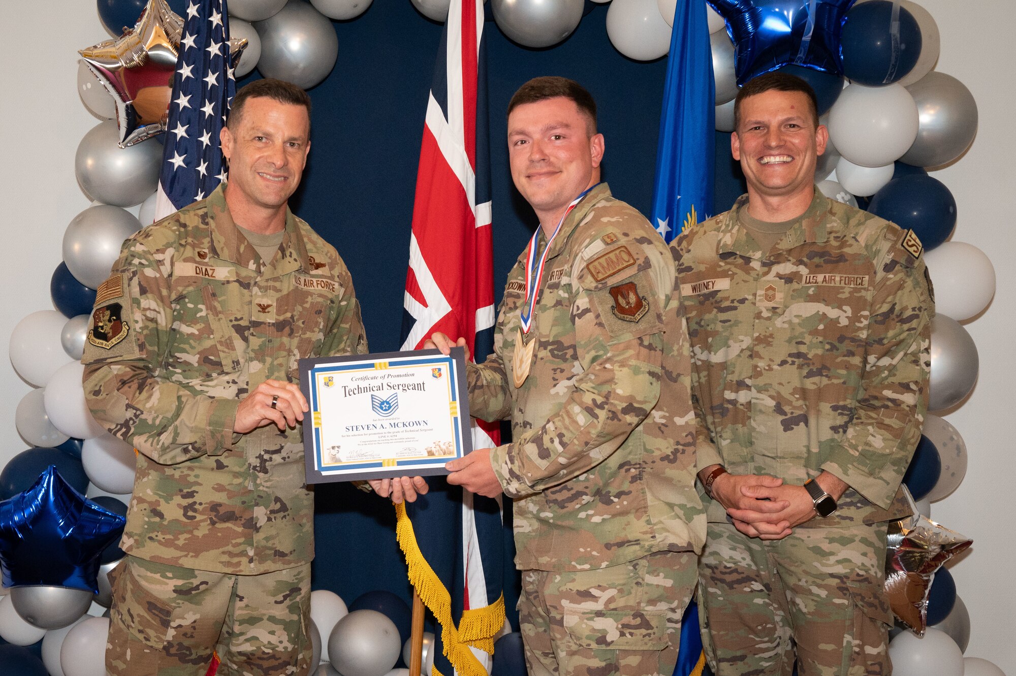 U.S. Air Force Col. Ricardo M. Diaz, left, 422nd Air Base Group commander, and Chief Master Sgt. Nicholas Whitney, right, 422nd Air Base Group senior enlisted leader, present a certificate of promotion to Staff Sgt. Steven A. Mckown, assigned to 420th Munitions Squadron.