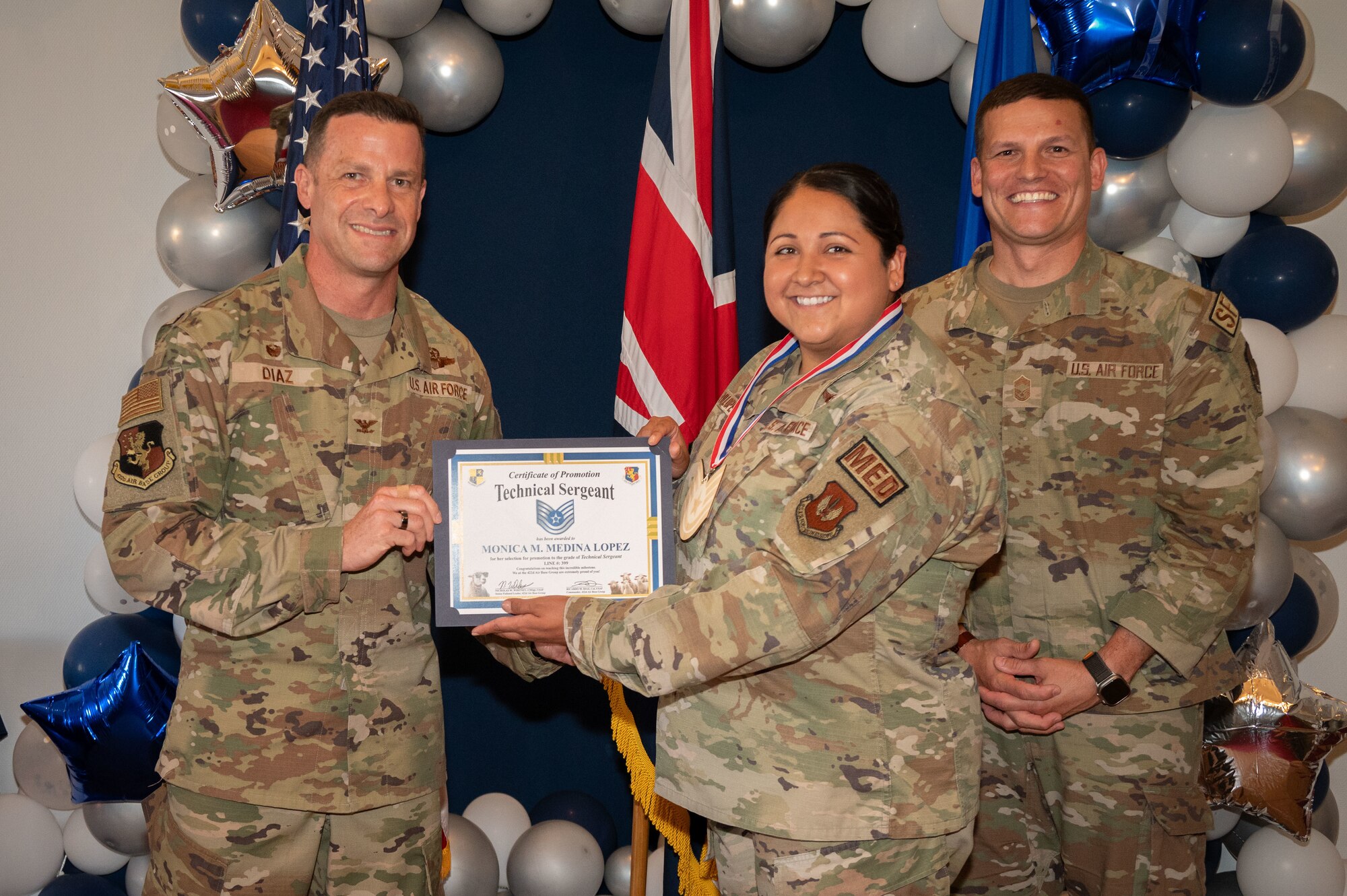 U.S. Air Force Col. Ricardo M. Diaz, left, 422nd Air Base Group commander, and Chief Master Sgt. Nicholas Whitney, right, 422nd Air Base Group senior enlisted leader, present a certificate of promotion to Staff Sgt. Monica M. Medina Lopez, assigned to the 422nd Medical Squadron.