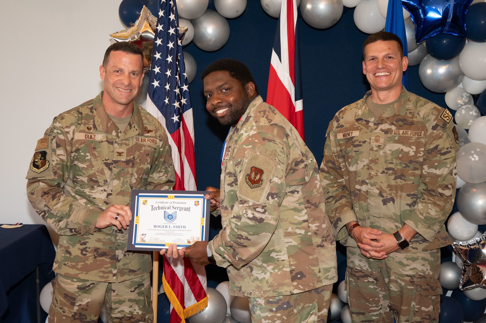 U.S. Air Force Col. Ricardo M. Diaz, left, 422nd Air Base Group commander, and Chief Master Sgt. Nicholas Whitney, right, 422nd Air Base Group senior enlisted leader, present a certificate of promotion to Staff Sgt. Roger L. Smith, assigned to the 422nd Medical Squadron.