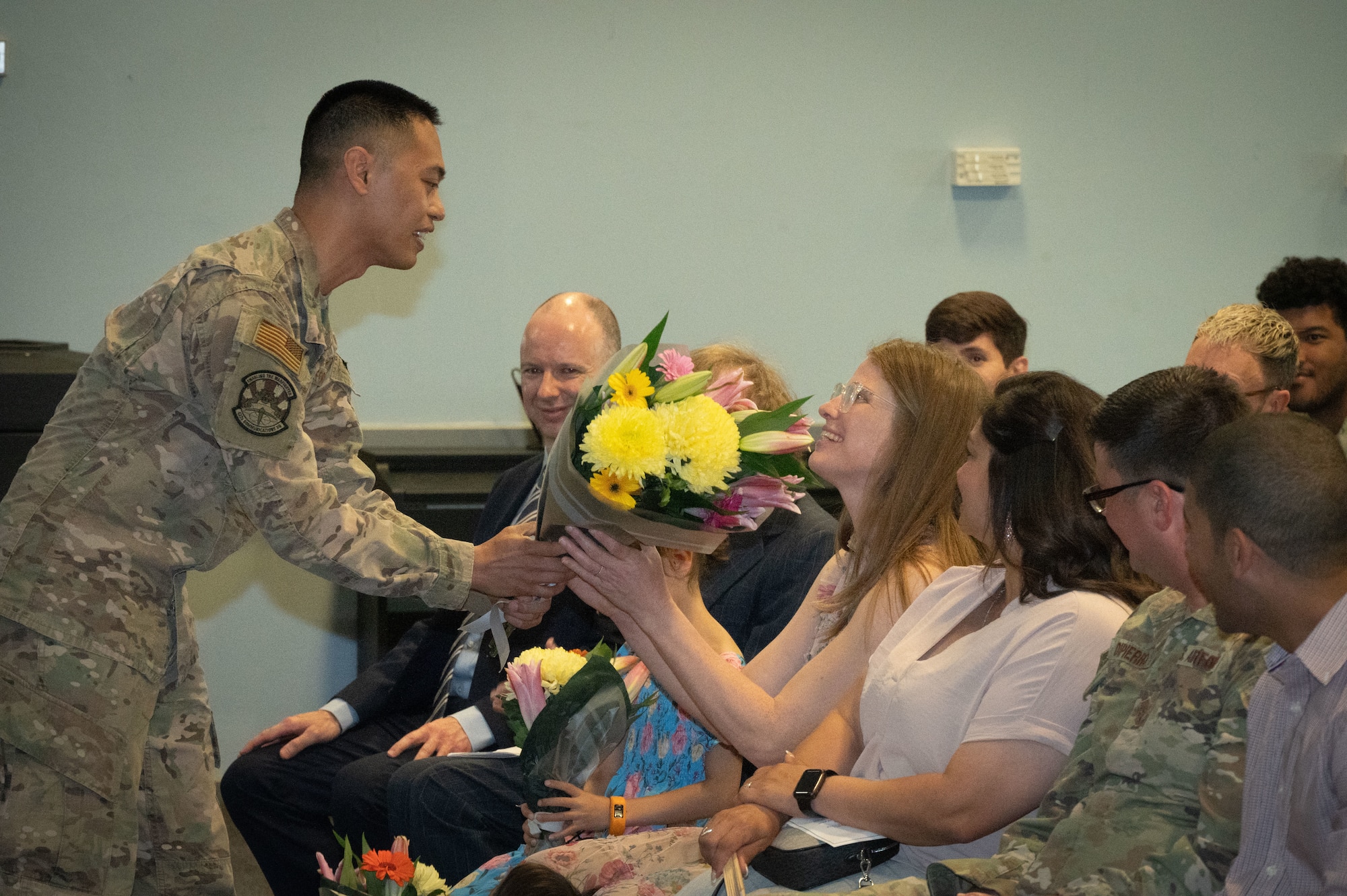 U.S. Air Force Maj. Francis Martin B. Gudez, 422nd Communications Squadron incoming commander, hands flowers to his wife and kids.