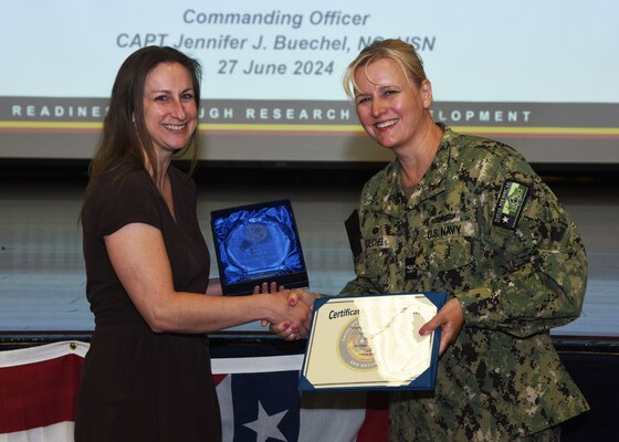 JOINT BASE SAN ANTONIO-FORT SAM HOUSTON – (June 27, 2024) – Dr. Leslie Neidert, a research physiologist assigned to Naval Medical Research Unit (NAMRU) San Antonio’s Combat Casualty Care and Operational Medicine Directorate, was recognized by Commanding Officer Capt. Jennifer Buechel (Nurse Corps) as the Fiscal Year 2024 “Science Staff” Civilian of the Half Year (First Half) during an All Hands meeting held at the Military and Family Readiness Center.  NAMRU San Antonio is one of the leading research and development laboratories for the U.S. Navy under the Department of Defense and is one of eight subordinate research commands in the global network of laboratories operating under the Naval Medical Research Center in Silver Spring, Md.  Its mission is to conduct gap driven combat casualty care, craniofacial, and directed energy research to improve survival, operational readiness, and safety of DOD personnel engaged in routine and expeditionary operations. (U.S. Navy photo by Burrell Parmer, NAMRU San Antonio Public Affairs/Released)