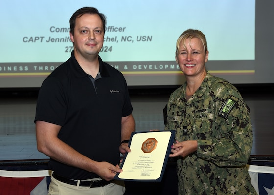 JOINT BASE SAN ANTONIO-FORT SAM HOUSTON – (June 27, 2024) – Dr. Clifford Morgan, a research cell biologist assigned to the Combat Casualty Care and Operational Medicine Directorate of Naval Medical Research Unit (NAMRU) San Antonio, was presented with a certificate of five years of service in the U.S. Government by Commanding Officer Capt. Jennifer Buechel (Nurse Corps) during an All Hands meeting at the Military and Family Readiness Center.  NAMRU San Antonio’s mission is to conduct gap driven combat casualty care, craniofacial, and directed energy research to improve survival, operational readiness, and safety of Department of Defense (DoD) personnel engaged in routine and expeditionary operations. It is one of the leading research and development laboratories for the U.S. Navy under the DoD and is one of eight subordinate research commands in the global network of laboratories operating under the Naval Medical Research Command in Silver Spring, Md. (U.S. Navy Photo by Burrell Parmer, NAMRU San Antonio Public Affairs/Released)