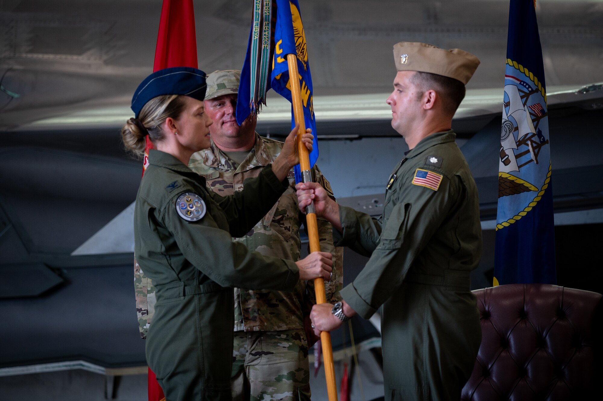 U.S. Air Force Col. Candice Sperry, 350th Spectrum Warfare Group commander, left, passes the guidon to U.S. Navy Cmdr. Alexander Sandroni, 513th Electronic Warfare Squadron commander, during the 513th EWS change of command ceremony at Eglin Air Force Base, Florida, June 18, 2024. The 513th EWS is responsible for providing mission data file reprogramming support to all United States F-35s. (Courtesy Photo)