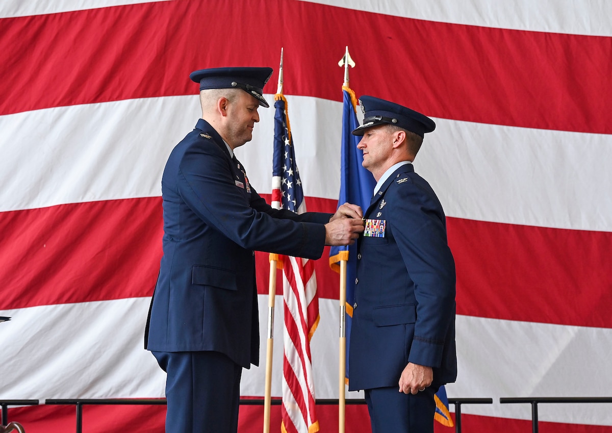 The wing commander pins a medal onto the jacket of a group commander