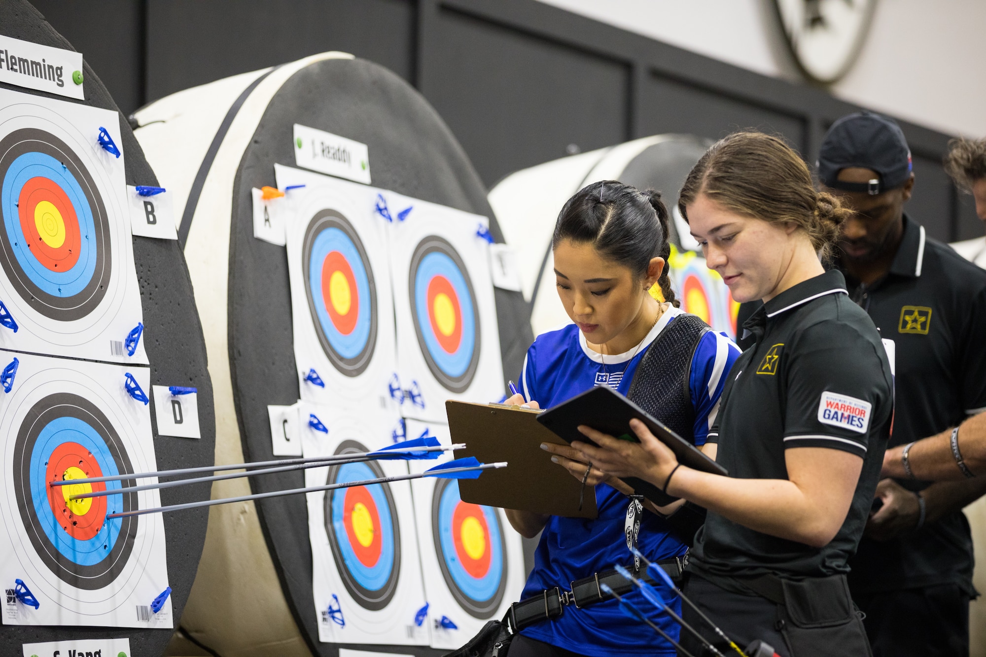 Athletes U.S. Air Force Capt. Christina Kang, Team Air Force, and Army Sgt. Bianca Hayden, Team Army, take notes of their targets and adjustments during the archery competition for the 2024 Department of Defense Warrior Games