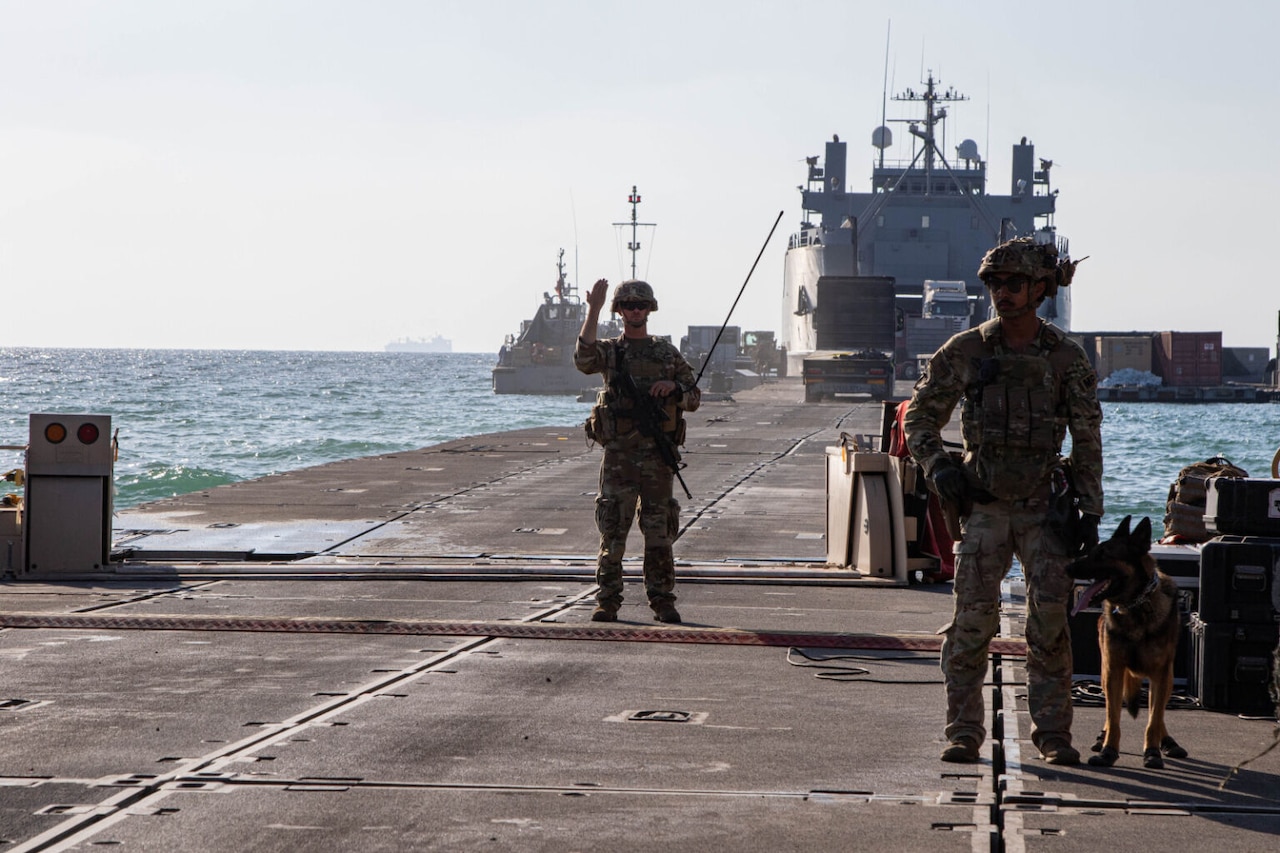 A service member makes a forward motion on a pier.