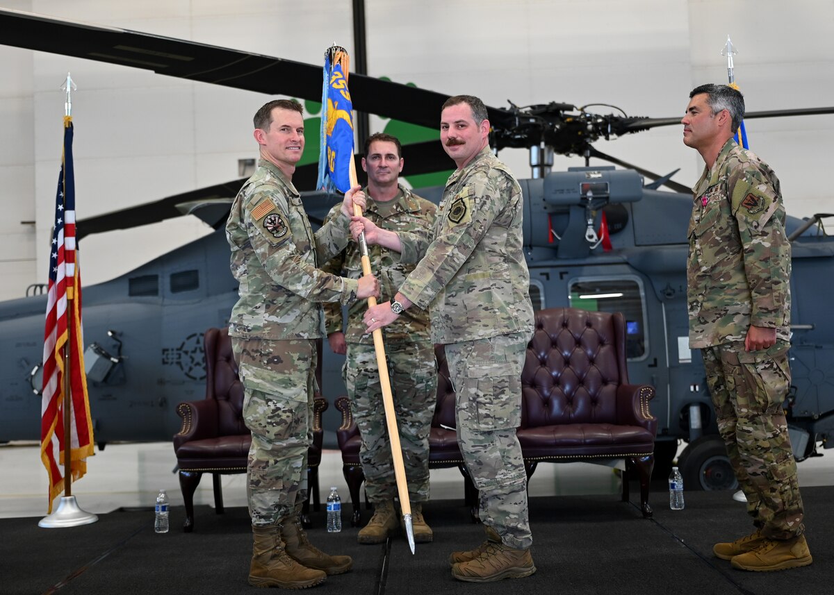 U.S. Air Force Col. Scott Mills, 355th Wing commander, left, presents the guidon to Col. Charles Redmond, 563rd Rescue Group incoming commander, during the 563rd RQG Change of Command at Davis-Monthan Air Force Base, Ariz., June 28, 2024. Redmond receiving the guidon represents him taking authority of the 563rd RQG. (U.S. Air Force photo by Staff Sgt. Abbey Rieves)