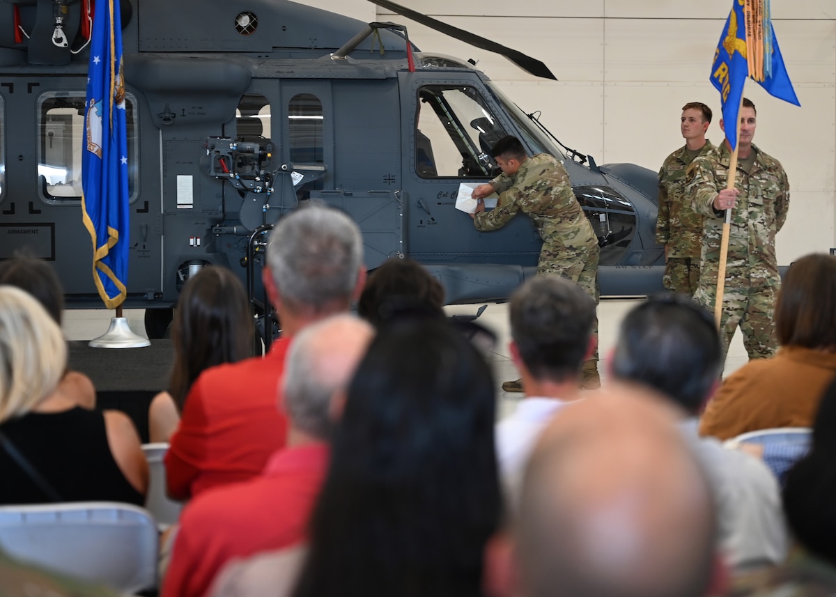 An U.S. Airman assigned to the 563rd Rescue Group reveals a decal on an HH-60W Jolly Green II helicopter during the 563rd Rescue Group Change of Command at Davis-Monthan Air Force Base, Ariz., June 28, 2024. The HH-60W was dedicated to the 563rd RQG’s incoming commander, Col. Charles Redmond. (U.S. Air Force photo by Staff Sgt. Abbey Rieves)