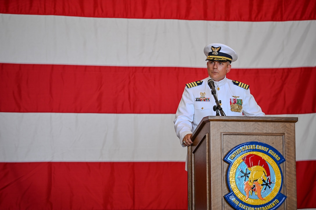 A Coast Guard officer stands at a podium while giving a speech
