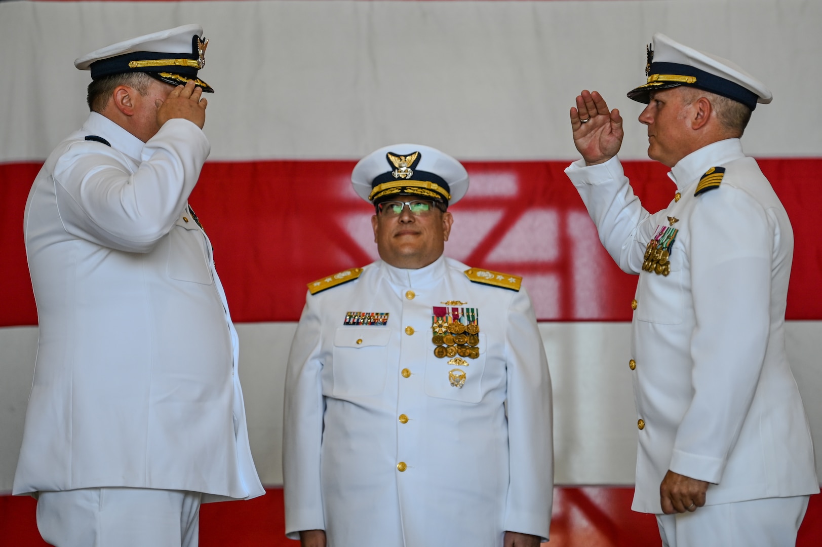 2 officers dress in white saluting each other