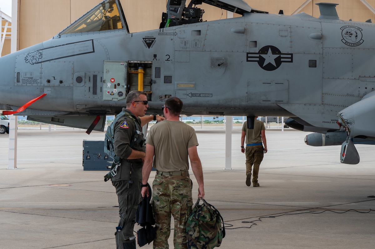 A photo of Airmen talking to each other in front of an A-10 aircraft.