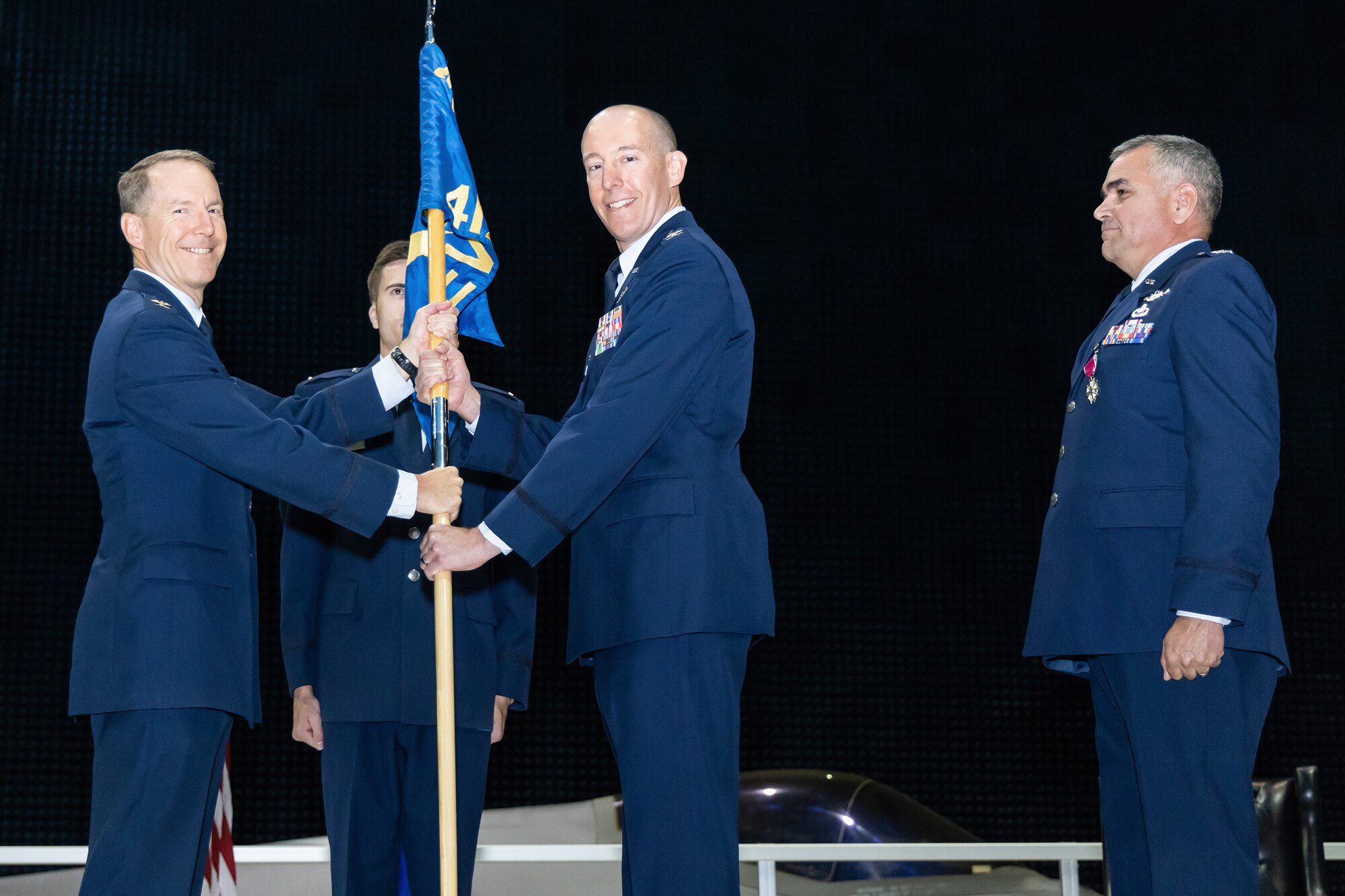 Col. Hans Buckwalter, the new 412th Electronic Warfare Group Commander, receives the unit guidon from Col. Douglas Wickert, 412th Test Wing Commander, during a change of command ceremony at the Benefield Anechoic Facility on Edwards Air Force Base, California, June 18.