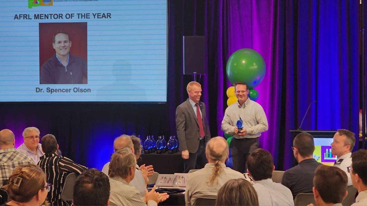 Gabe Mounce, director AFRL Tech Engagement Office, awards Dr. Spencer Olson, AFRL Space Vehicles Directorate Tech Engagement Office, the inaugural AFRL Mentor of the Year Award at the 2024 New Mexico Excellence in STEM Awards ceremony, Q Station, AFRL’s Tech Engagement Office’s collaborative facility, Albuquerque, N.M., June 21, 2024. The award was given to Olson as a cumulative recognition to the value of his work with the AFRL Scholars program since 2013. The AFRL-sponsored event recognizes significant science, technology, engineering and math education endeavors throughout the state. (Courtesy photo)
