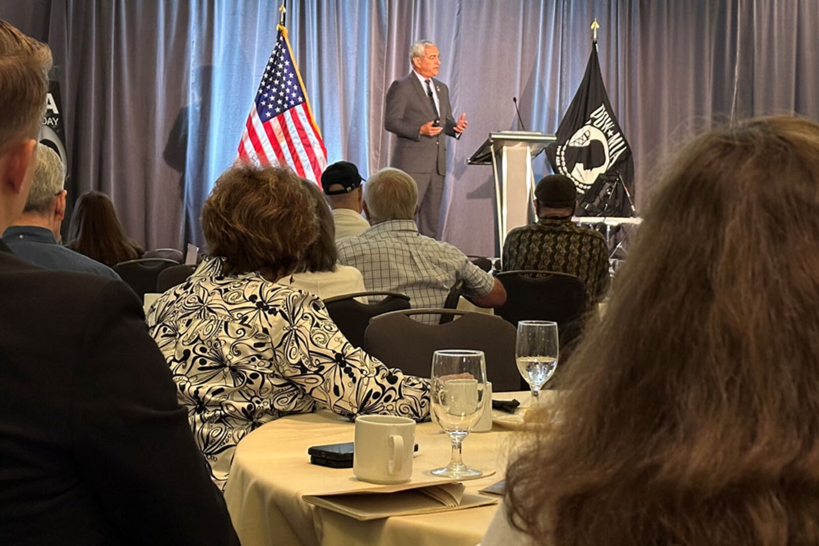 A man speaks to a group of military and civilian personnel.