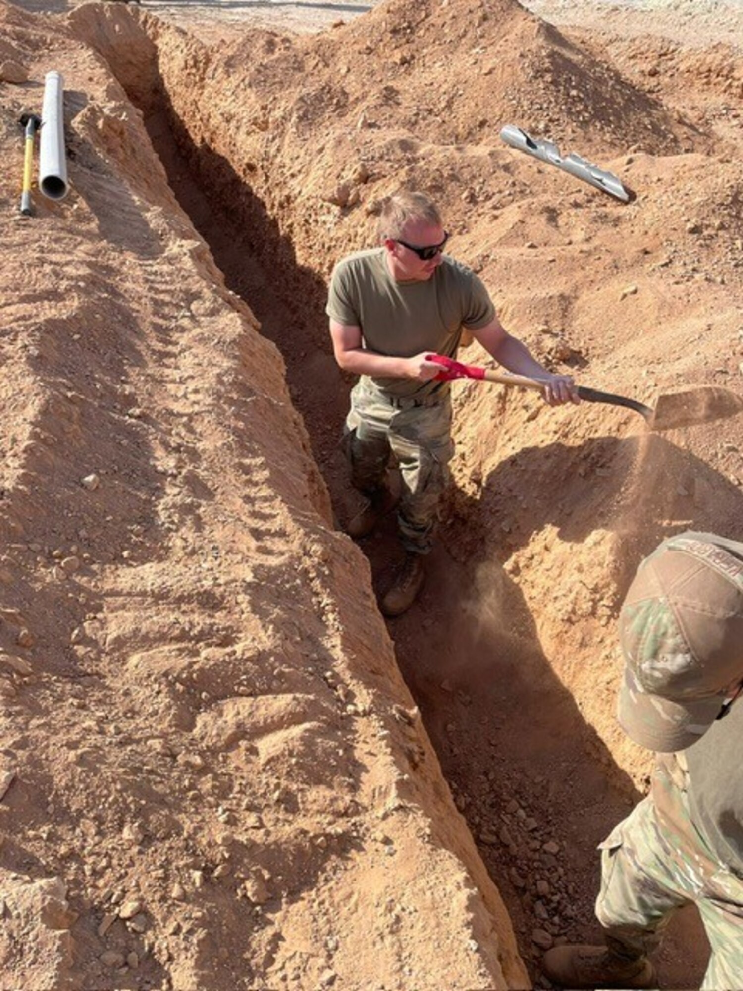 Airmen assigned to the 1st Expeditionary Theater Support Group dig a ditch for a conduit install at an undisclosed location within the U.S. Central Command area of responsibility, June 3, 2024. One of the ETSG’s main objectives is campaigning and setting the theater for Agile Combat Employment through prepositioning vital equipment, creating detailed bed down plans, contracting local support services, establishing communications nodes, and executing ground preparation engineering projects. (U.S. Air Force Courtesy photo)