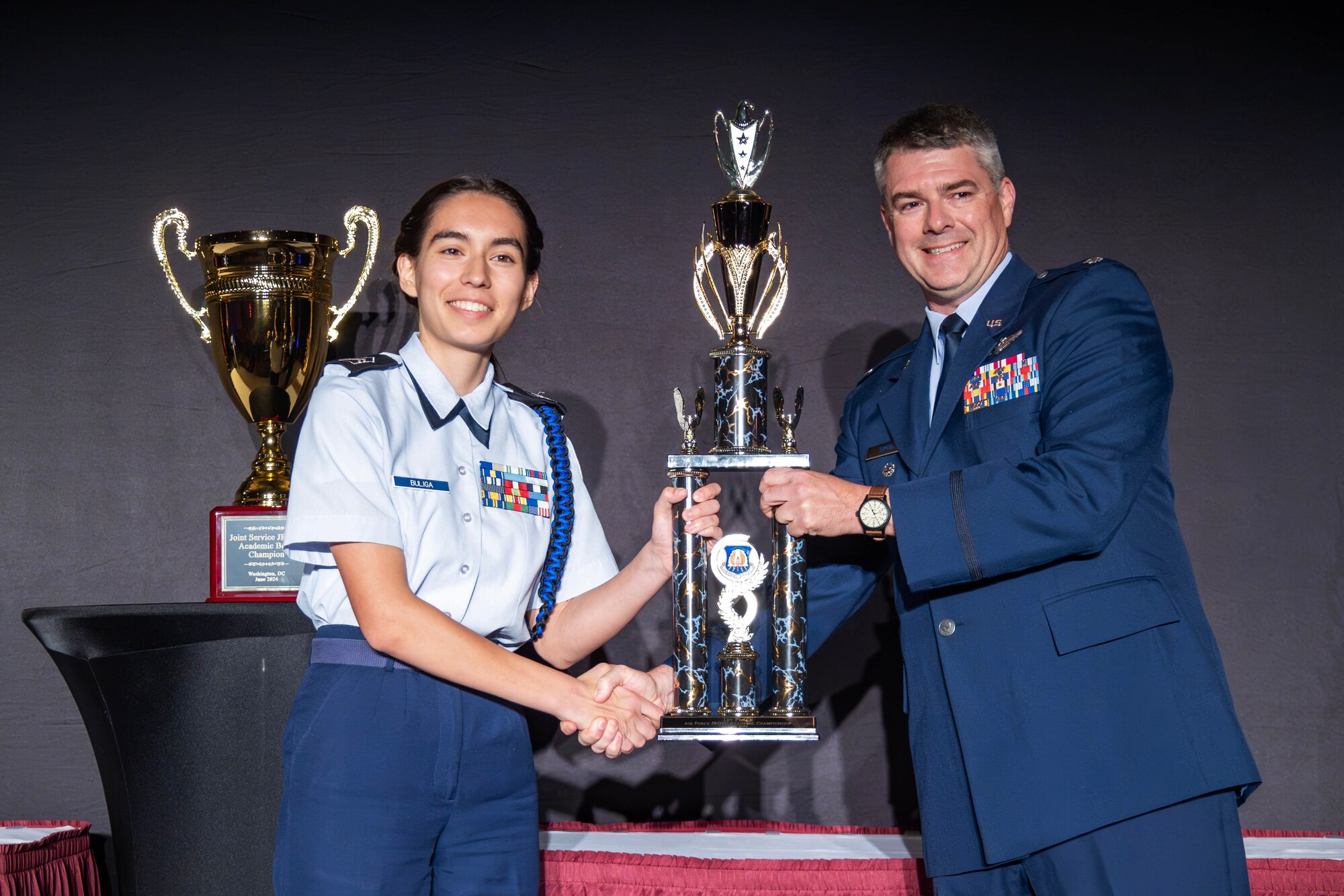 Lt. Col Matthew Tipton, Director, Air Force Junior ROTC presents the Air Force Championship trophy to Cadet Emma Buliga from Valencia High School at the 2024 JROTC Leadership and Academic Bowl on June 23 in Washington D.C.