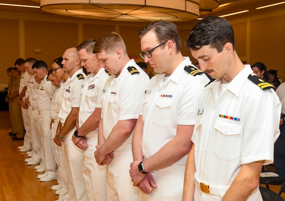 Camp Lejeune Family Medicine Residency Program residents stand at attention for the National Anthem and parading of the colors during the commencement ceremony at Marston Pavilion, on June 28, 2024. The ceremony celebrated the graduation of 10 residents, 10 interns, and two sports medicine fellows who will go on to their next duty stations around the world to continue practicing medicine.