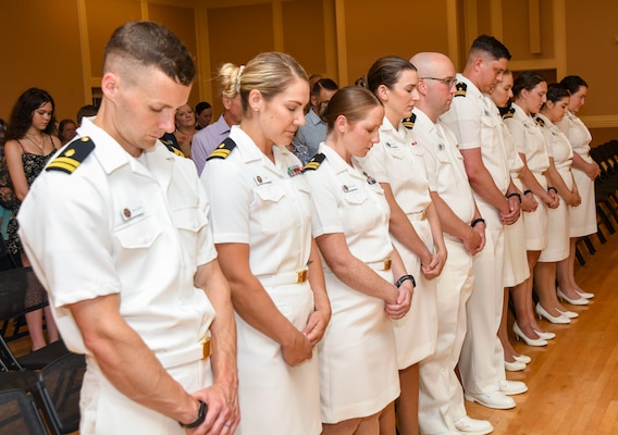 Camp Lejeune Family Medicine Residency Program interns stand at attention for the National Anthem and parading of the colors during the commencement ceremony at Marston Pavilion, on June 28, 2024. The ceremony celebrated the graduation of 10 residents, 10 interns, and two sports medicine fellows who will go on to their next duty stations around the world to continue practicing medicine.