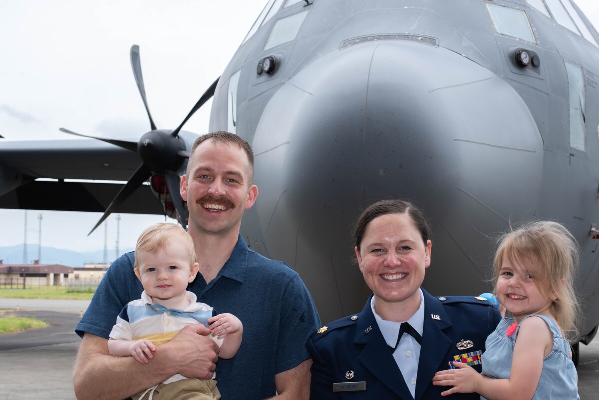 A family poses for a photo in front of a C-130J Super Hercules.