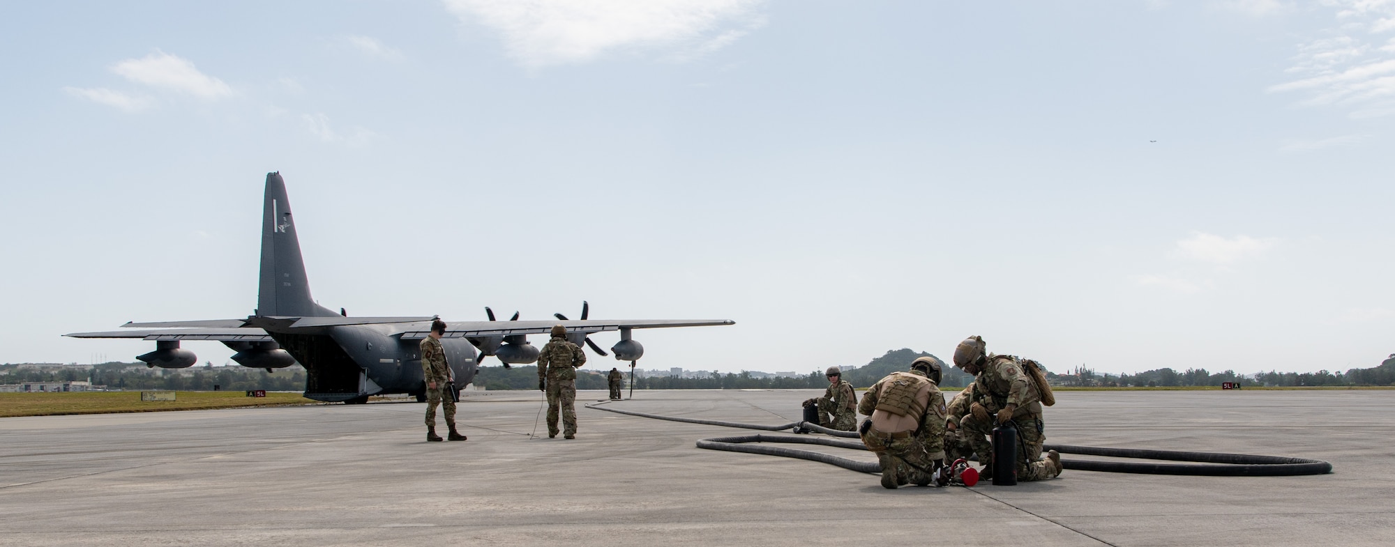 A transport plane is prepared for refueling operations by several Airmen.