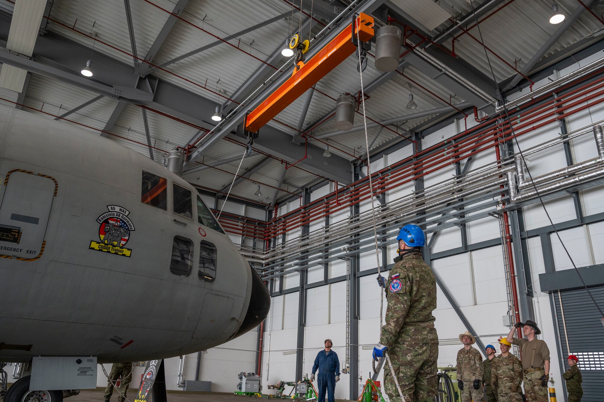 A man uses a rope to guide a crane over an aircraft