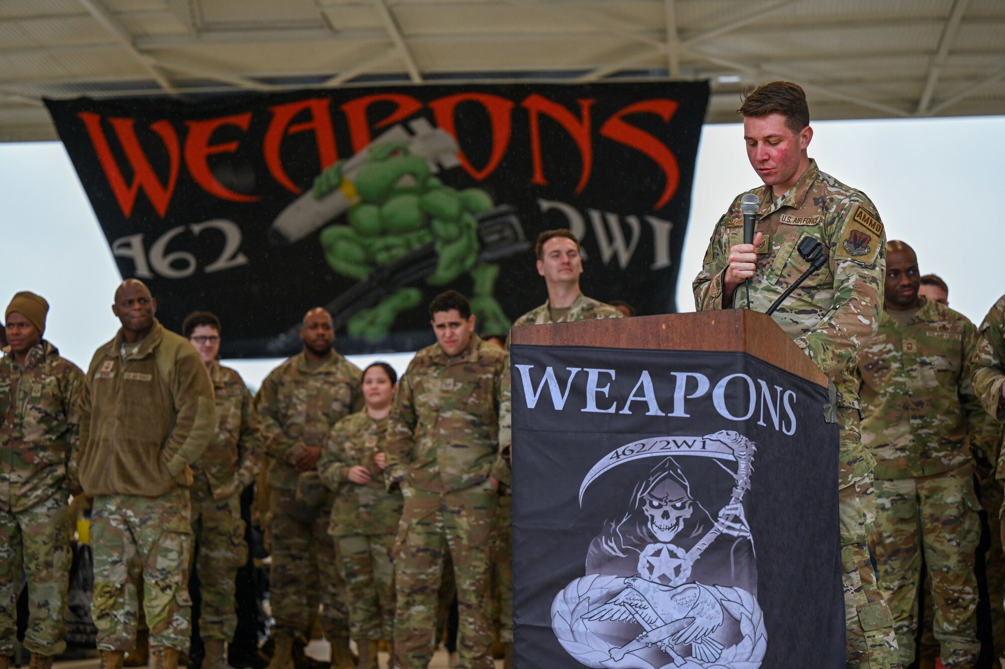 U.S. Air Force Technical Sgt. Sean Marcotte, a munitions inspections productions supervisor assigned to the 4th Munitions Squadron, announces during an annual weapons load competition at Seymour Johnson Air Force Base, North Carolina, Feb. 23, 2024. Every year, a load crew from each unit goes head-to-head in a competition that tests their dress and appearance, weapons knowledge and speed and accuracy of loading munitions on an F-15E Strike Eagle. (U.S. Air Force photo by Staff Sgt. Koby I. Saunders)